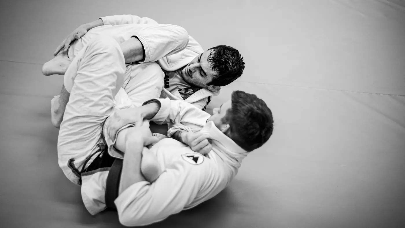 Two grapplers in gis, one playing guard