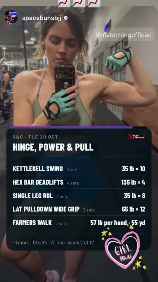 A member's gym mirror selfie above her MatStrong session card: kettlebell swings, hex bar deadlifts 135 lb for 4, single-leg RDLs, pulldowns and farmer's walks, week 2 of 12
