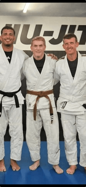 Robert in his brown belt on the mats with two training partners